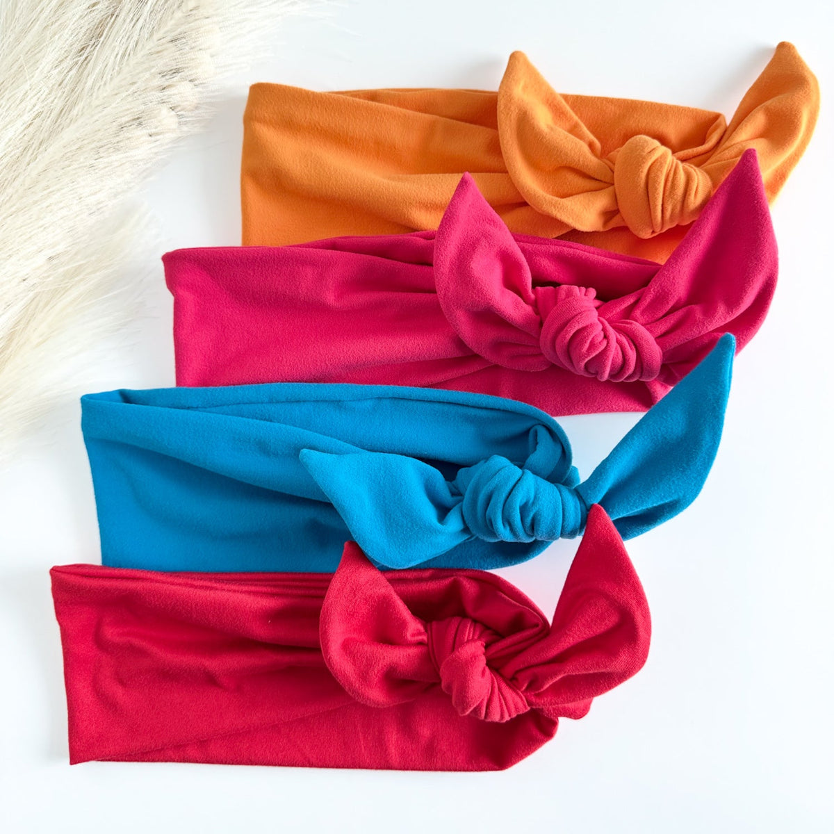 Headband Studio adjustable tie headbands in red, blue, pink, and orange. Soft, stretchy fabric with knotted detail.