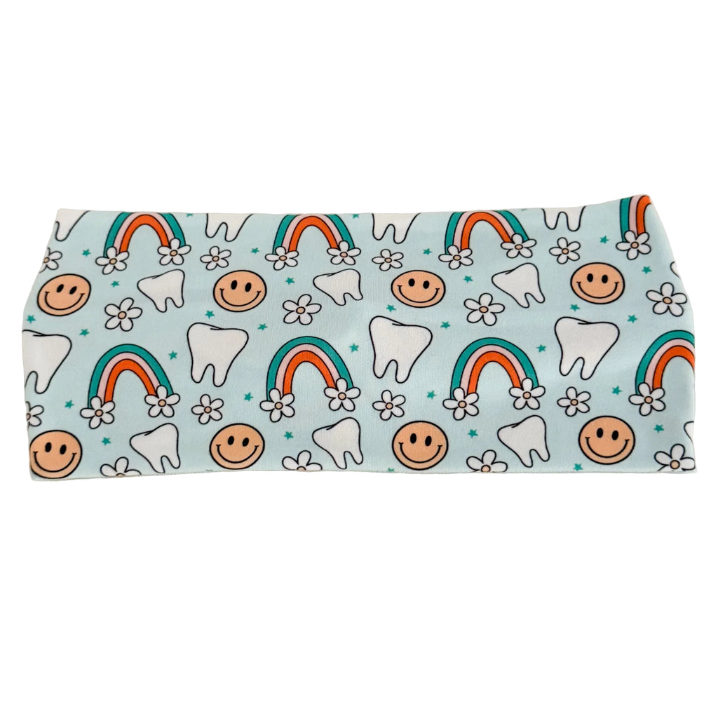 Fabric with tooth, smiley face, and rainbow pattern on a light blue background