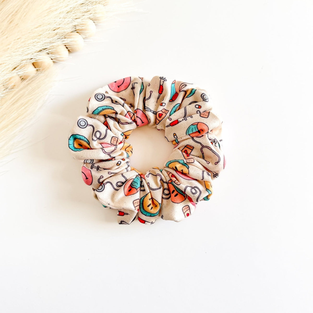 Headband Studio cream scrunchie with medical print: stethoscopes, syringes, band-aids, and smiley faces.