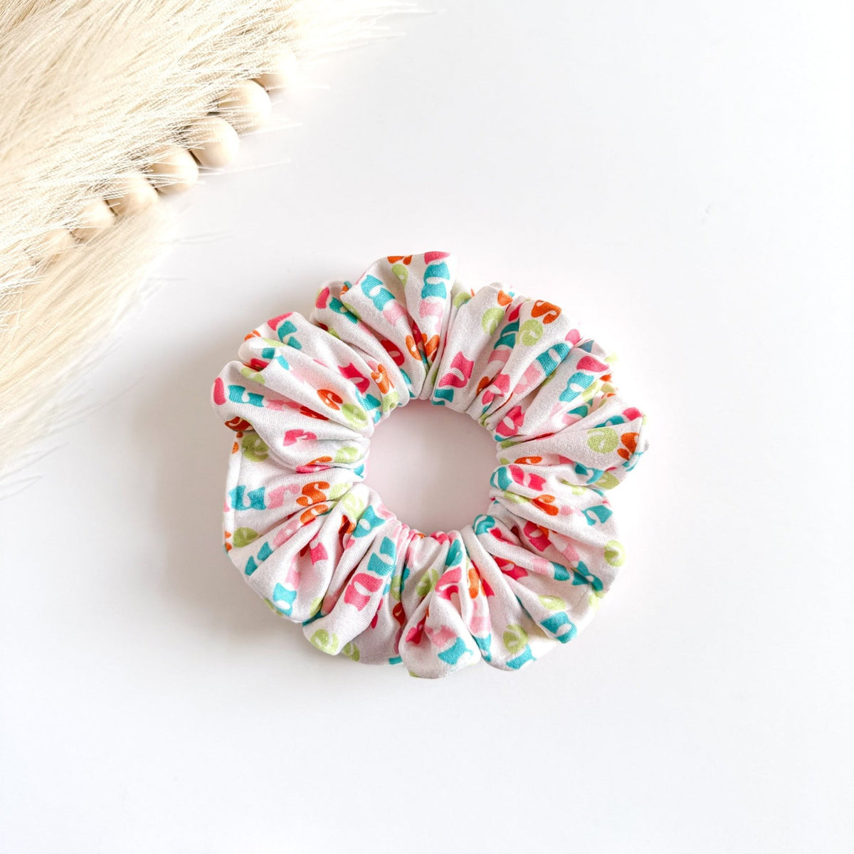Headband Studio white scrunchie with colorful nurse letter print, perfect for nurses and healthcare workers.