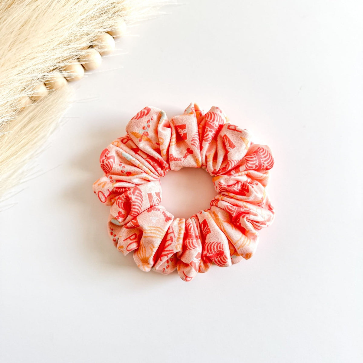 Headband Studio peach scrunchie with a repeating pattern of small medical icons in orange and yellow.