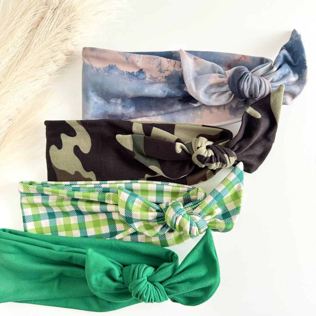 Headband Studio adjustable tie headbands in blue marble, camouflage, green plaid, and solid green. Soft fabric, knotted design.