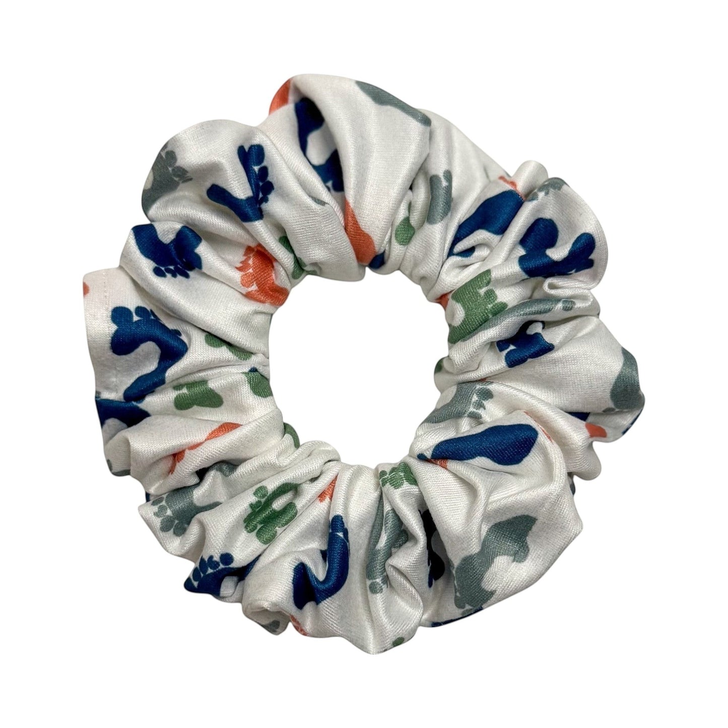 Headband Studio white scrunchie with a repeating pattern of blue, green, and orange footprints. Made from soft polyester.