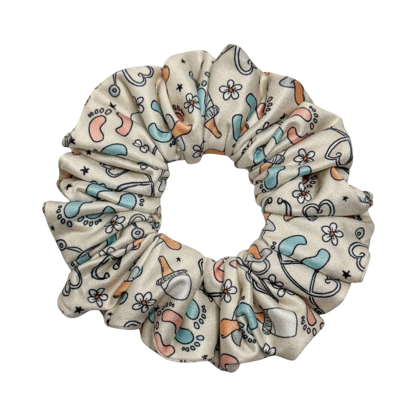 Headband Studio cream scrunchie with a medical print featuring baby feet, pacifiers, and flowers in blue and peach.