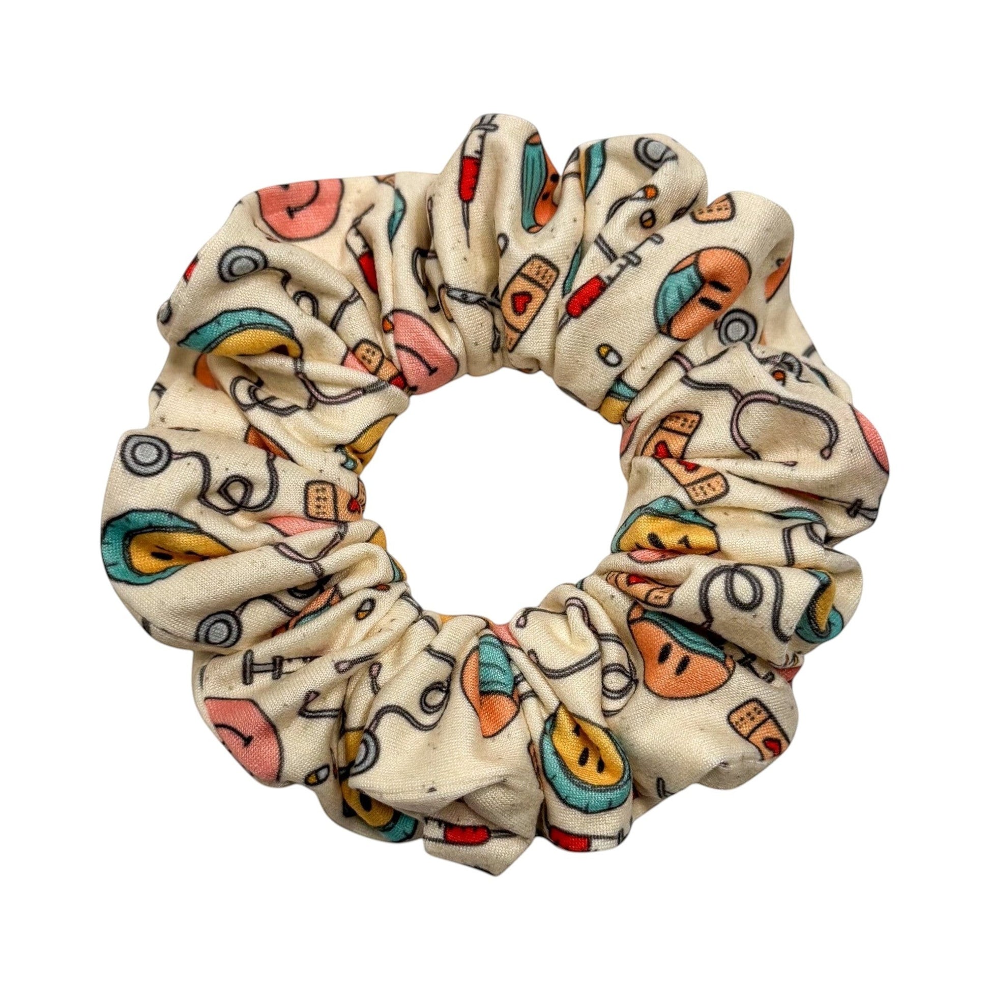 Headband Studio cream scrunchie with medical print: stethoscopes, syringes, band-aids, and smiley faces.
