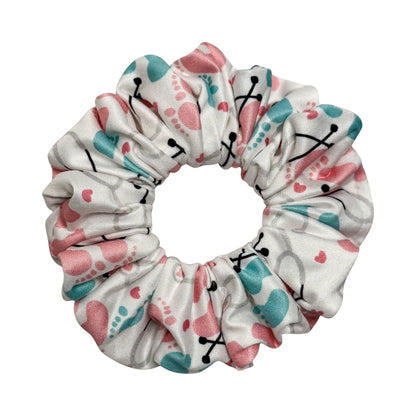 Headband Studio white scrunchie with pink and teal footprints and stethoscopes pattern, made of soft polyester.