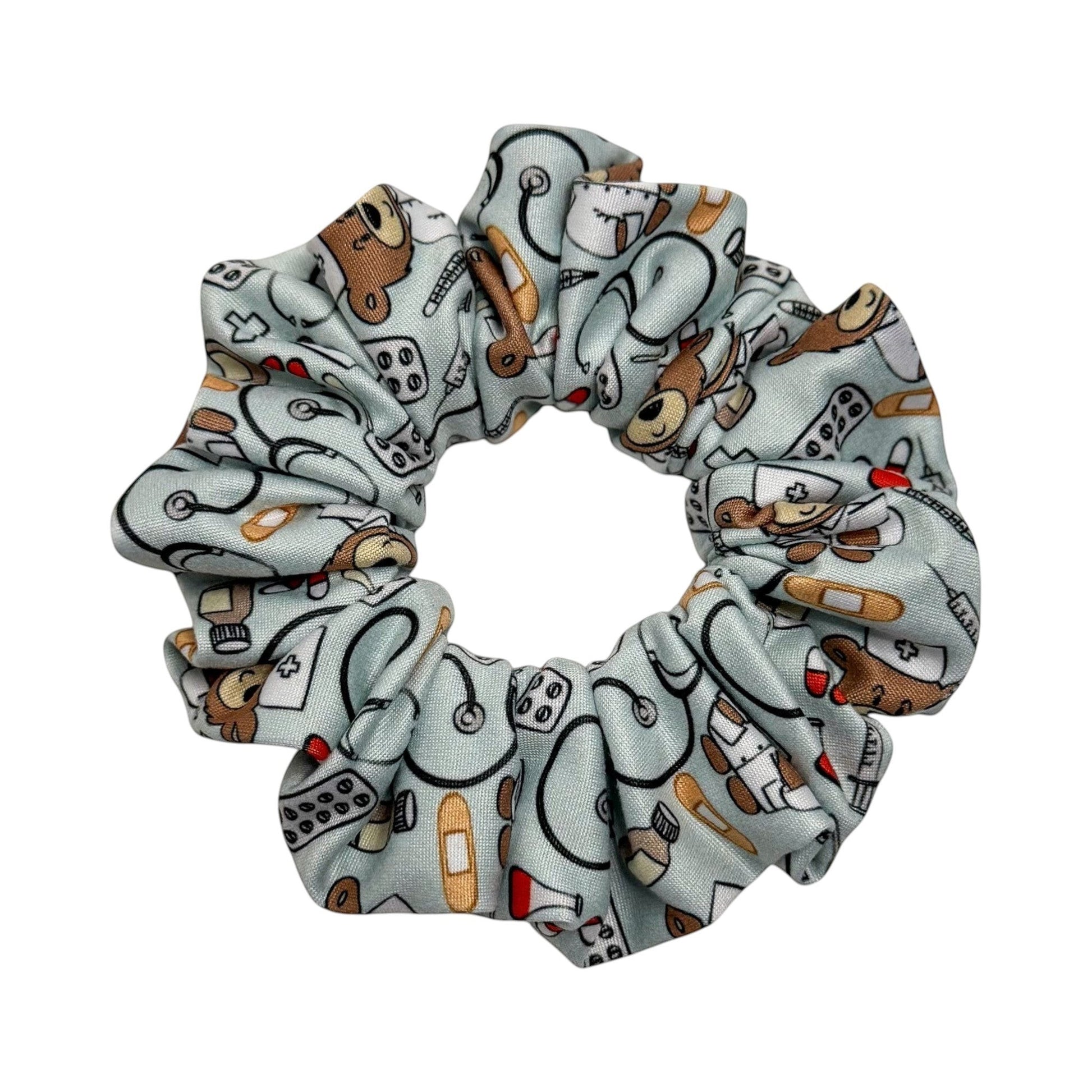 Headband Studio light blue scrunchie with a pattern of medical icons like stethoscopes, band-aids, pills, and teddy bears in nurse outfits.