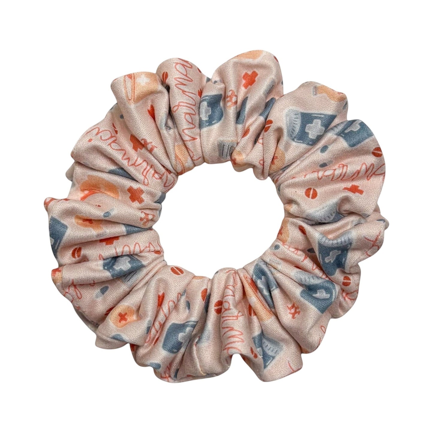 Headband Studio pink scrunchie with medical icons like stethoscopes, pills, and crosses. Handmade from soft polyester.