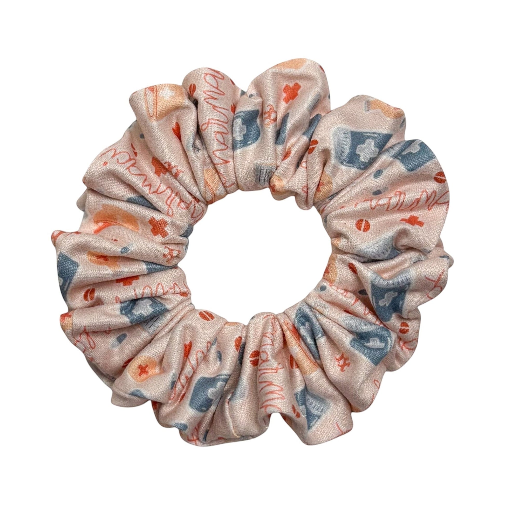 Headband Studio pink scrunchie with medical icons like stethoscopes, pills, and crosses. Handmade from soft polyester.