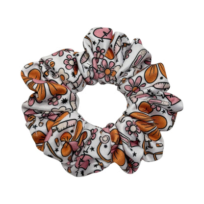 Headband Studio white scrunchie with pink and orange medical-themed print, including flowers, stethoscopes, and syringes.
