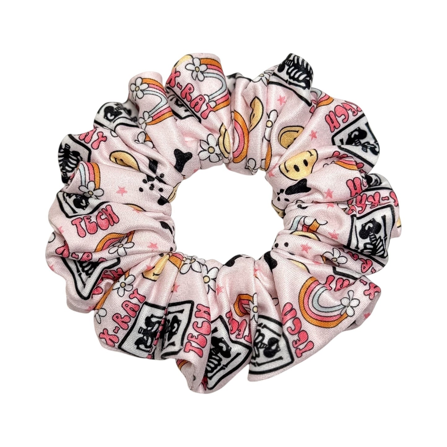 Headband Studio pink scrunchie with medical tech print, featuring X-ray images, rainbows, and flowers. Handmade from soft polyester.