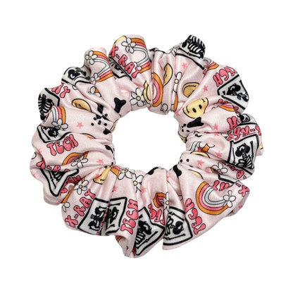 Headband Studio pink scrunchie with medical tech print, featuring X-ray images, rainbows, and flowers. Handmade from soft polyester.