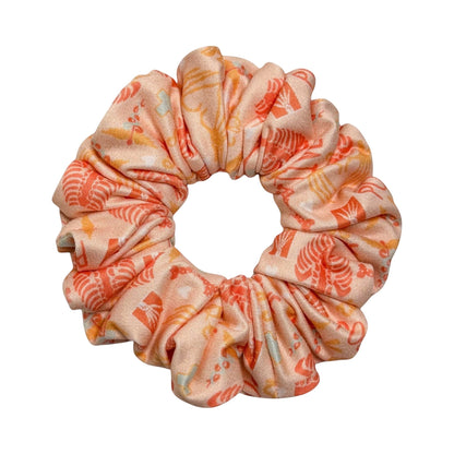 Headband Studio peach scrunchie with a repeating pattern of small medical icons in orange and yellow.