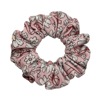 Headband Studio pink scrunchie with a white floral print and black outlines, made of soft polyester.
