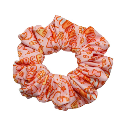 Headband Studio pink scrunchie with orange medical icons like stethoscopes, syringes, and pills.