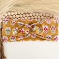 Sugar skull twist headband with white floral sugar skulls on mustard gold
