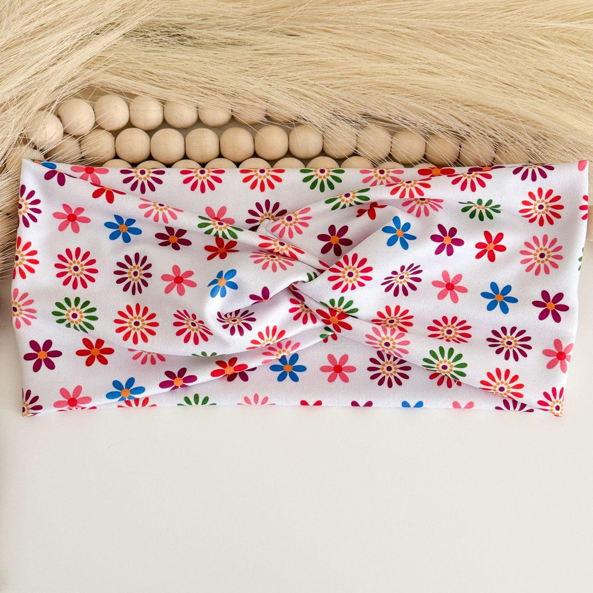 Colorful flowers twist headband with red, pink, blue, green and burgundy daisies on white