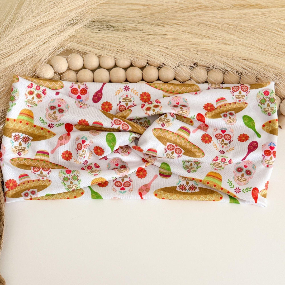 Day of the Dead twist headband with sugar skulls, sombreros, maracas and red flowers on white
