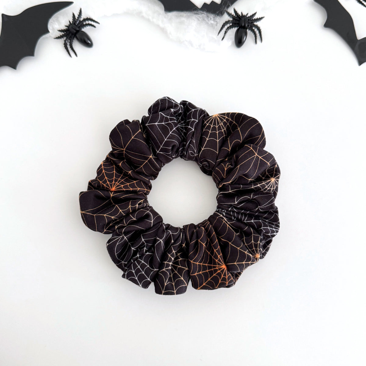 Midnight Webs scrunchie with orange spider webs on black