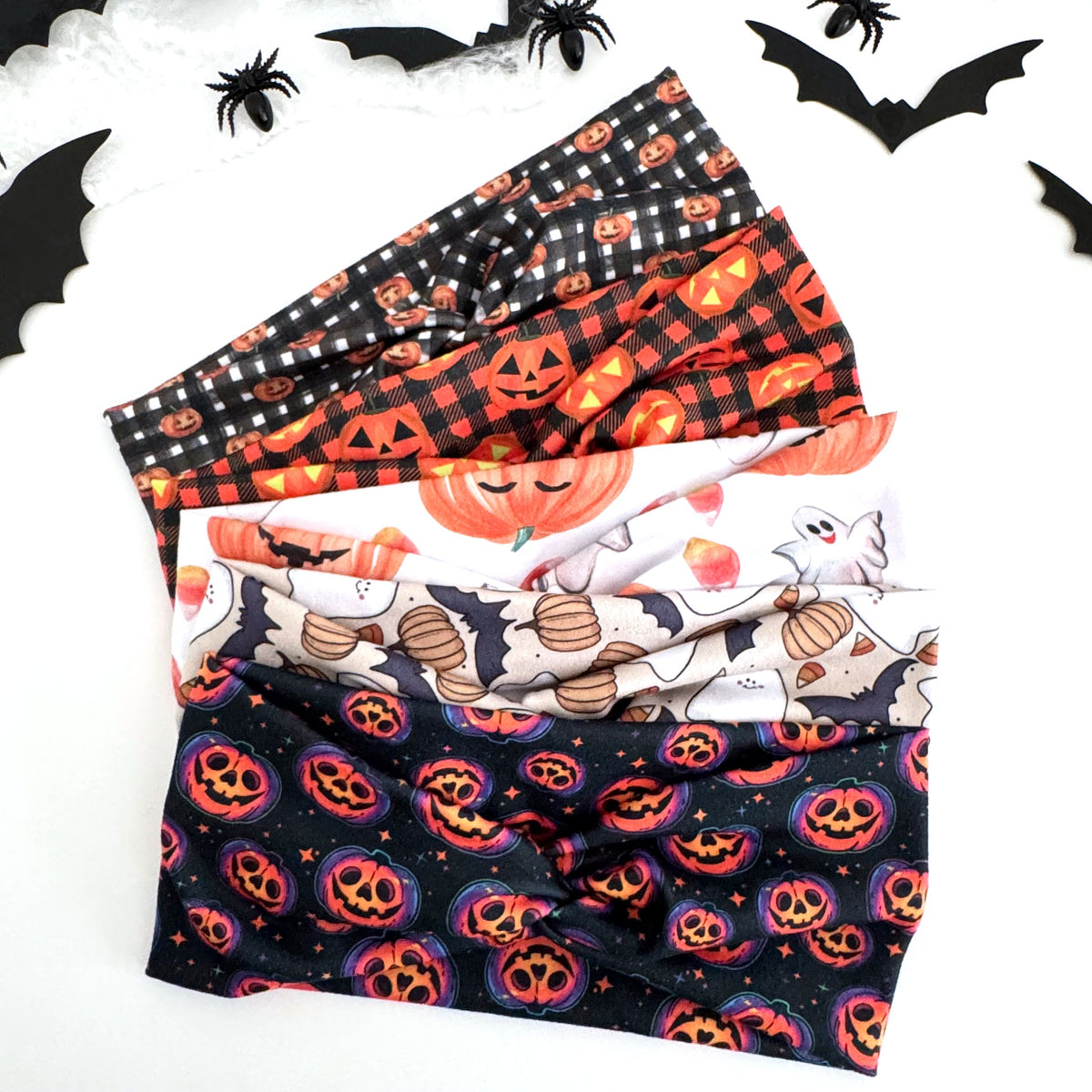 Pumpkin Halloween twist headbands fanned out with paper bats and spiders