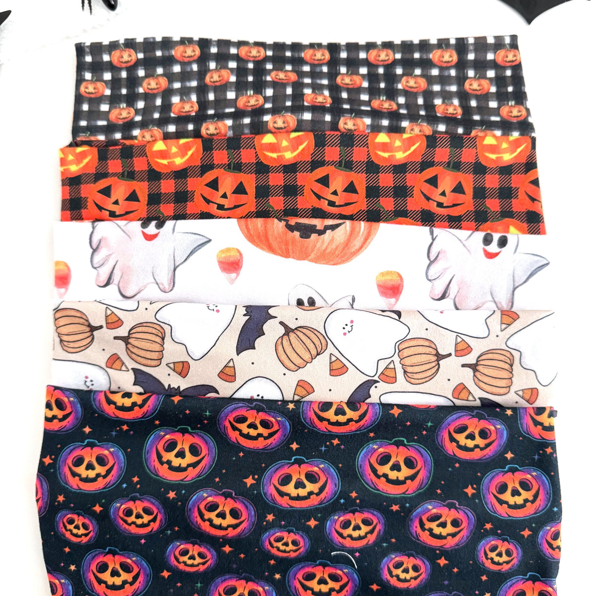 Pumpkin twist headbands stacked: Gingham Pumpkin, Plaid Pumpkin, Pumpkin and Candy Corn, Ghost and Pumpkins and Glowing Jack-o'-Lanterns